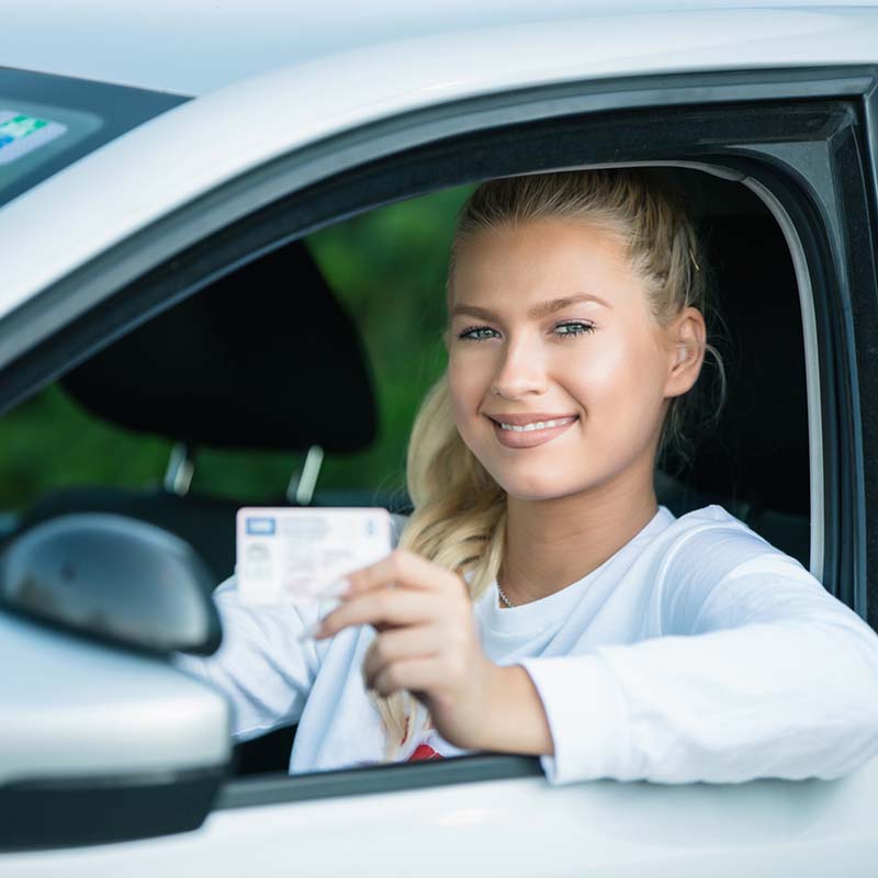Female driving student showing drivers license Female driving student showing drivers license