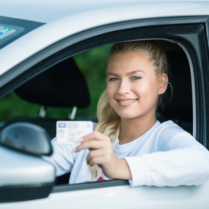 Female driving student showing drivers license